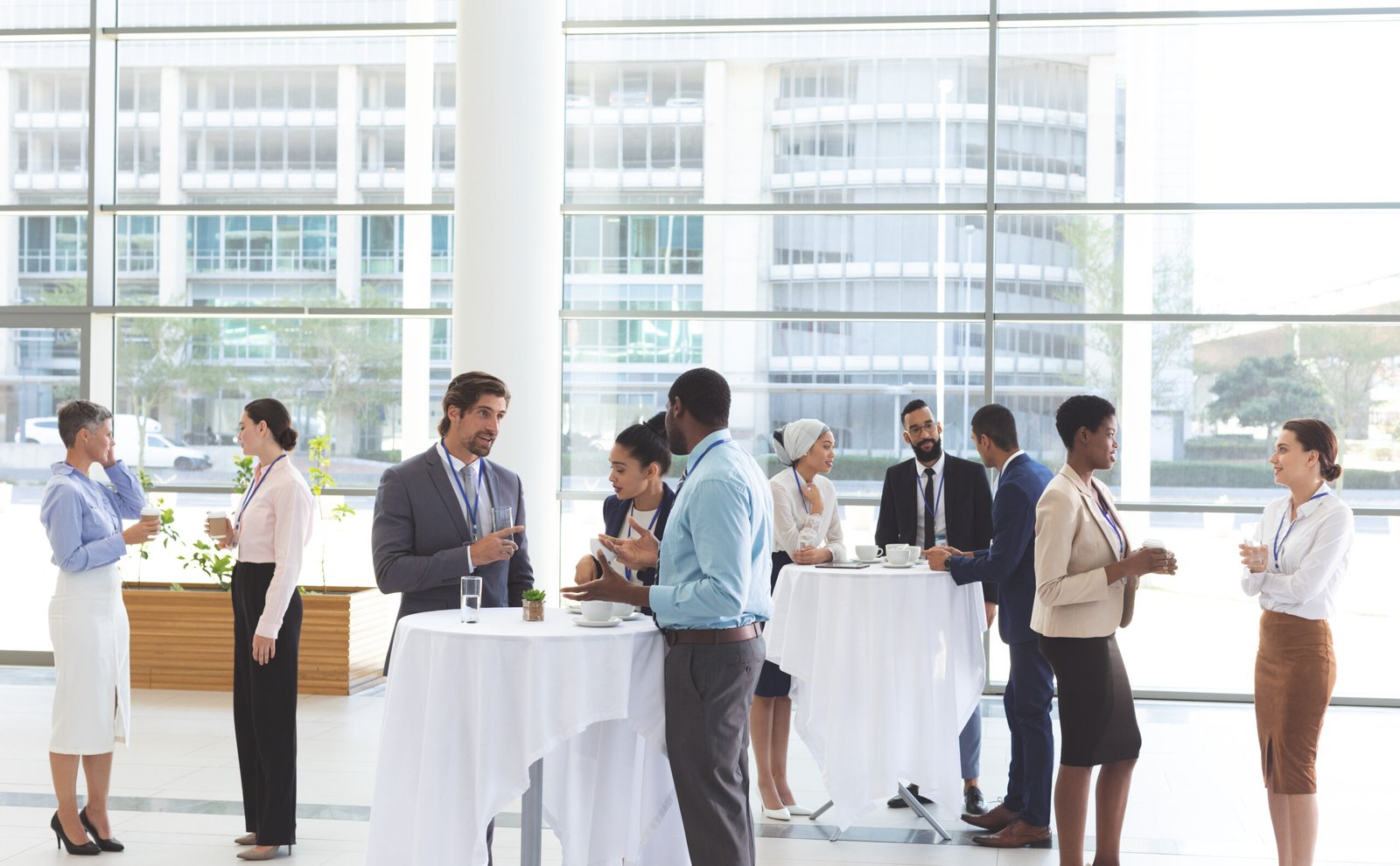 Front view of diverse business people interacting with each other at table after a conference in office lobby